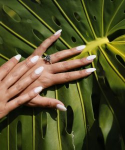 a woman's hands with white manicures and a ring